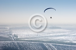 paramotor seen from the sky in France flying over snowy fields i